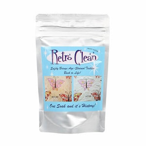May include: A silver pouch with a blue and white label that says "Retro Clean" and "Safely Brings Age-Stained Textiles Back to Life!" The label also shows a before and after image of a fabric with a butterfly design. The text on the label says "One Soak and it's History!"