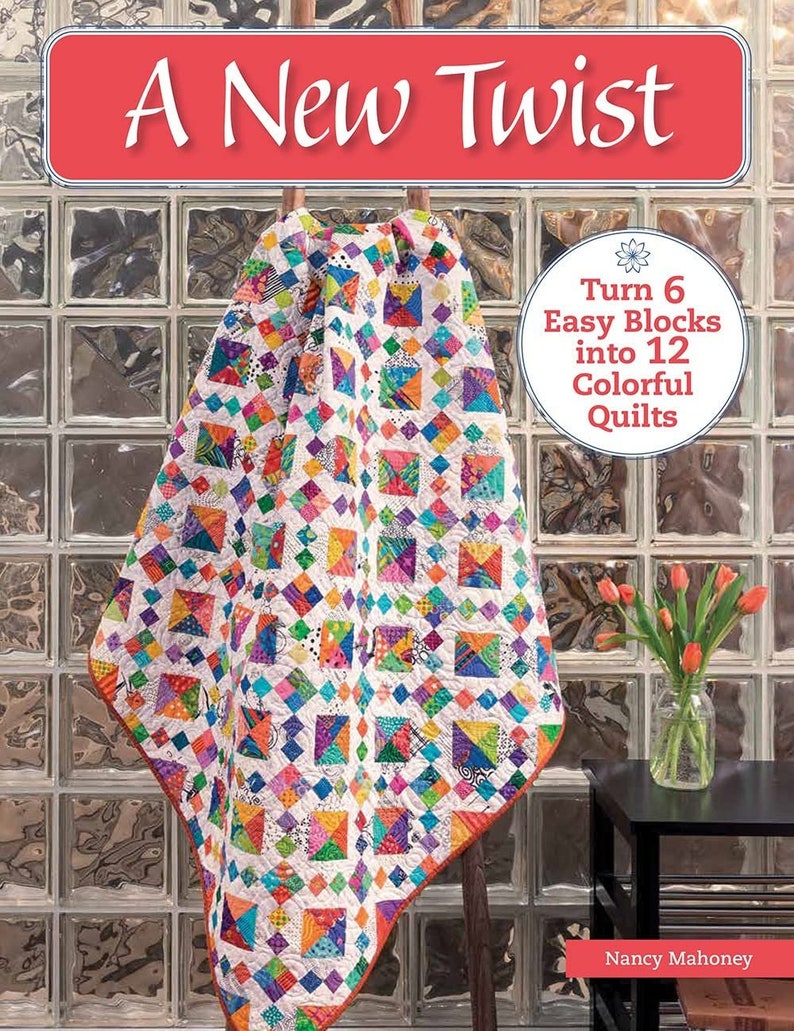 May include: A book titled "A New Twist" featuring a colourful quilt on the cover. The book cover also includes the text "Turn 6 Easy Blocks into 12 Colorful Quilts".