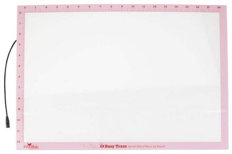 K&ouml;nnte beinhalten: Ein rechteckiges Lichtpad mit einer wei&szlig; beleuchteten Mitte und einem rosa Rand, der an der Ober- und linken Seite aufgedruckte Lineale von 0 bis 45,7 cm horizontal und 0 bis 30,5 cm vertikal aufweist, inklusive eines schwarzen Stromkabels.