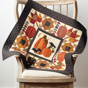 May include: A quilt pattern featuring a pumpkin patch design with two black birds and a crescent moon. The quilt is 30 inches by 30 inches and is called "Pumpkin Patch Quilt".