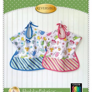 May include: Two reversible toddler bibs with a colorful animal print on one side and a striped pattern on the other. The bibs are hanging on hooks and have a neck opening. The text "Ultimate Toddler Bib" and "Reversible" is visible on the image. The image also includes the text "Shabby Fabrics.com" and a logo with the text "Shabby Fabrics".