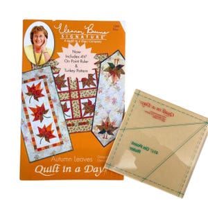 May include: A quilting pattern book titled "Autumn Leaves Quilt in a Day" by Eleanor Burns Signature. The book features a photo of a woman and three quilt designs. The book includes a 4 1/2 inch on-point ruler and a turkey pattern.