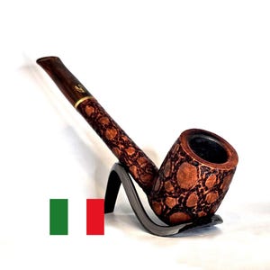 May include: A brown tobacco pipe with a textured, spotted pattern. The pipe rests on a black stand, showcasing its curved design. The mouthpiece is dark brown with a gold band.