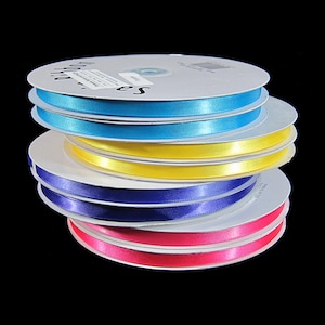 May include: A stack of spools of satin ribbon in turquoise, yellow, purple, and pink colors. The ribbon is wrapped around white cardboard spools.