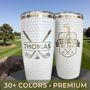 Peut inclure: Deux gobelets blancs sur le thème du golf avec des accents argentés. L'un porte le nom "Thomas" avec des clubs de golf croisés et une balle. L'autre dit "BEST DAD BY PAR" avec une silhouette de golfeur.