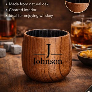 May include: A wooden whiskey tumbler with a charred interior, engraved with the name "Johnson". The tumbler is made from solid oak and is designed for enjoying whiskey. The text "CHARRED OAK WHISKEY TUMBLER" is at the top.