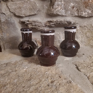 May include: Three brown ceramic vases with white accents. The vases have a textured, woven design and a rounded, bulbous shape.