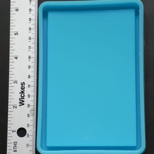 May include: A light blue silicone mould for resin casting. The mould is rectangular with a raised edge around the perimeter.