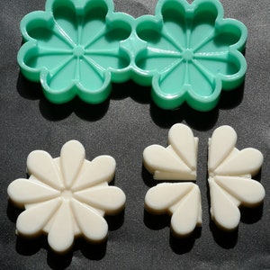May include: Two green silicone moulds shaped like a daisy flower. Two white daisy flower shapes made from the moulds.