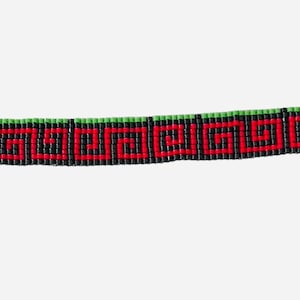May include: A beaded choker necklace with a geometric pattern in red, black, and green. The necklace has gold-colored clasps and an adjustable chain. The design features a repeating Greek key pattern.