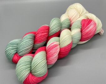 Puede incluir: Un ovillo de hilo con un patrón de color verde, rosa y blanco. El hilo está retorcido en un bucle.