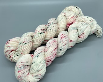 May include: White yarn with red and green speckles. The yarn is twisted into a loop.