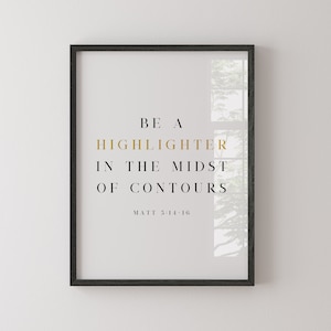 May include: Black framed print with a white background and gold text that reads "Be a Highlighter in the Midst of Contours Matt 5:14-16". The print features a blurry image of trees through a window.