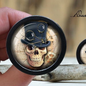 May include: A black and white skull wearing a top hat with goggles and a clock face background. The skull is wearing a black top hat with a gold band and goggles. The background is a clock face with Roman numerals and gears.