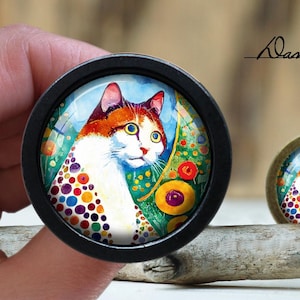 May include: A colorful, abstract painting of a white cat with orange and brown markings. The cat is surrounded by colorful dots and flowers. The painting is framed in a black circle.