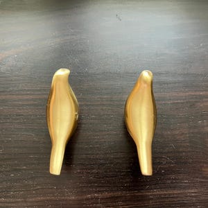 Pu&ograve; includere: Due ganci da parete a forma di uccello color oro.