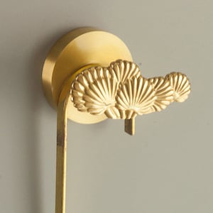 Könnte beinhalten: Vergoldeter Toilettenpapierhalter aus Metall mit einem dekorativen Fächerdesign.