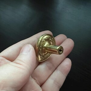 May include: A gold-toned heart-shaped cabinet knob with a decorative design and a screw-on post.