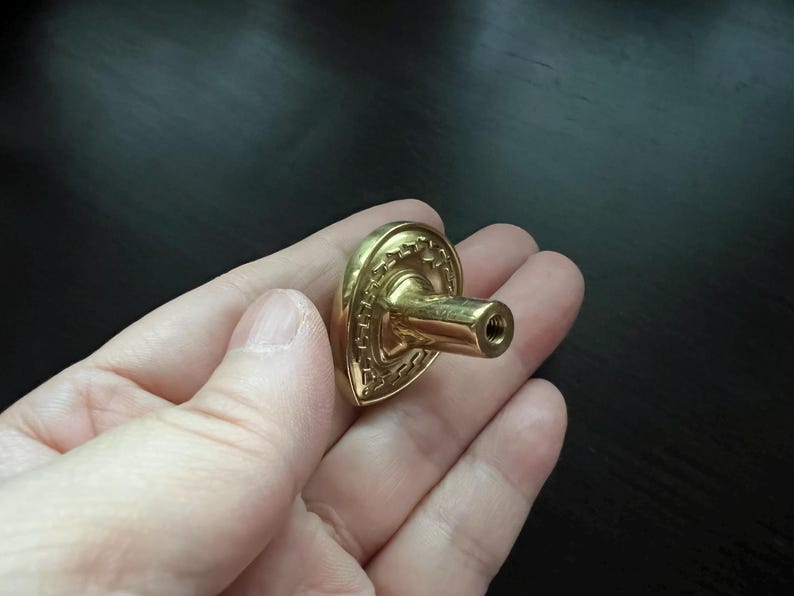 May include: A gold-toned heart-shaped cabinet knob with a decorative design and a screw-on post.
