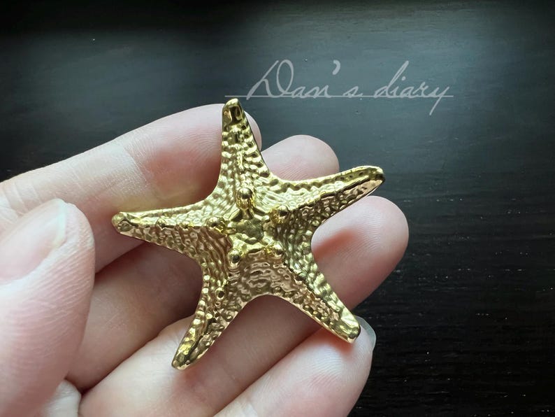 May include: A gold-coloured starfish charm with a textured surface.