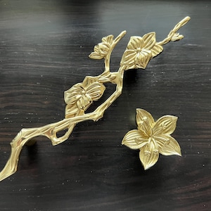 May include: Gold-toned metal drawer pull in the shape of a stylised floral branch with five blossoms.
