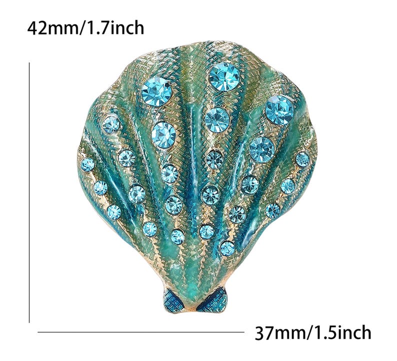 May include: A seashell brooch, measuring 42mm wide and 37mm tall, with a teal and gold finish. The brooch is embellished with numerous round, light blue rhinestones, adding sparkle to the design.