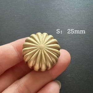 Puede incluir: Un pomo decorativo redondo de color dorado con un dise&ntilde;o de rayos de sol. El pomo mide 25 mm de di&aacute;metro. S: 25mm