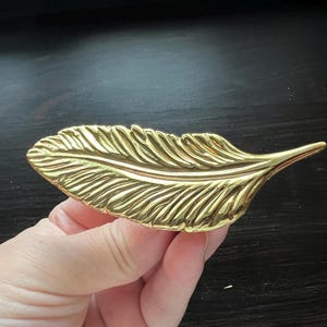 以下が含まれることがあります： 金色の金属製の羽根の形をした装飾品