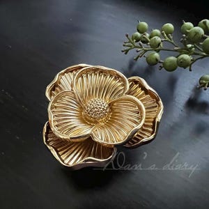 May include: A gold-coloured metal flower-shaped decorative knob with a textured surface.