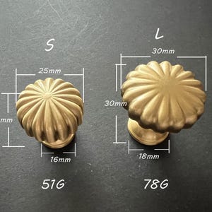 Puede incluir: Dos pomos de armario de color dorado con un dise&ntilde;o acanalado. El pomo m&aacute;s peque&ntilde;o mide 25 mm de di&aacute;metro y 16 mm de alto. El pomo m&aacute;s grande mide 30 mm de di&aacute;metro y 18 mm de alto.