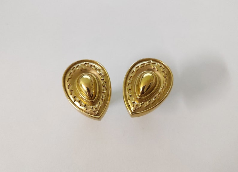 May include: A pair of gold-tone teardrop-shaped earrings with a textured design.