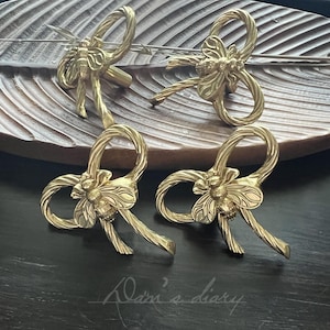 Peut inclure: Quatre poignées de tiroir en métal doré en forme de nœuds avec un motif d'abeille au centre.