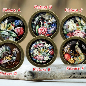 May include: Six round, gold-toned metal cabochons with glass domes, each featuring a different hand-painted design of birds and flowers. The designs include a hummingbird, a peacock, and various other birds and floral arrangements.