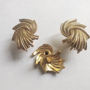 K&ouml;nnte beinhalten: Drei goldfarbene, spiralf&ouml;rmige Schrankkn&ouml;pfe. Die Kn&ouml;pfe haben ein strukturiertes, geriffeltes Design und ein zentrales Schraubenloch zur Befestigung. Die Hardware ist wahrscheinlich f&uuml;r M&ouml;bel oder dekorative Zwecke bestimmt.