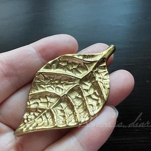 Könnte beinhalten: Ein Set aus drei Keramikbechern mit gesprenkelter, matter Oberfläche. Die Becher sind in Creme-, Hellgrau- und Dunkelgrautönen gehalten. Jeder Becher hat ein schlichtes, minimalistisches Design und einen abgerundeten Henkel.