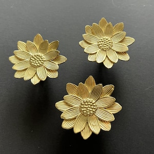 May include: Three gold-coloured metal sunflower-shaped drawer pulls.
