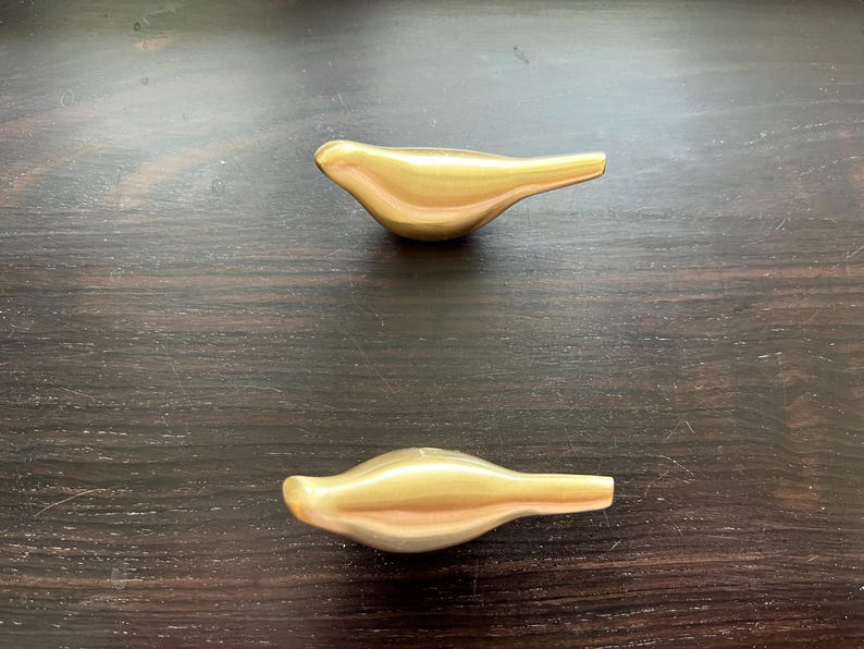 Pu&ograve; includere: Due pomelli per porte a forma di uccello di colore dorato.