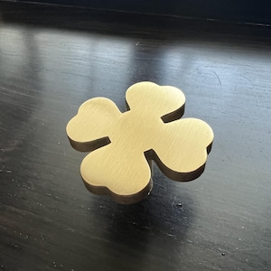 May include: A gold-coloured metal four-leaf clover shaped coaster.