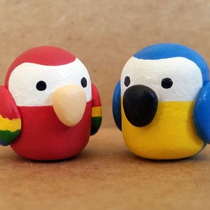 May include: Two small clay bird figurines, one red with green, yellow, and blue accents and the other blue with yellow and white accents.