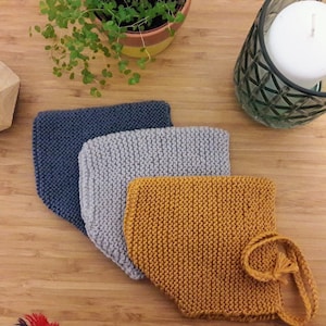 Peut inclure: Trois bonnets en tricot pour bébé dans différentes couleurs : bleu, gris et jaune. Les bonnets sont disposés sur une surface en bois.