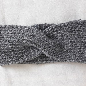 May include: A gray knitted headband with a twisted design.
