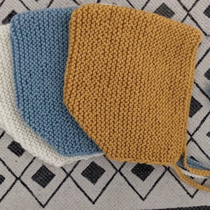 Peut inclure: Trois bonnets de bébé en tricot blanc, bleu et jaune. Les bonnets sont pliés et empilés les uns sur les autres. Les bonnets ont de longues attaches.