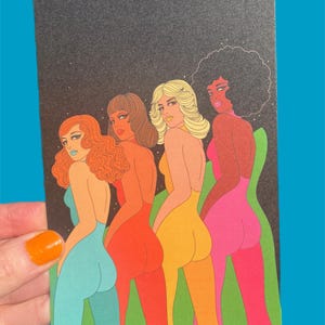 May include: A black rectangular art print featuring four figures in colorful bodysuits, each with a different skin tone and hairstyle. The figures are posed with their backs to the viewer, set against a dark background with white specks.