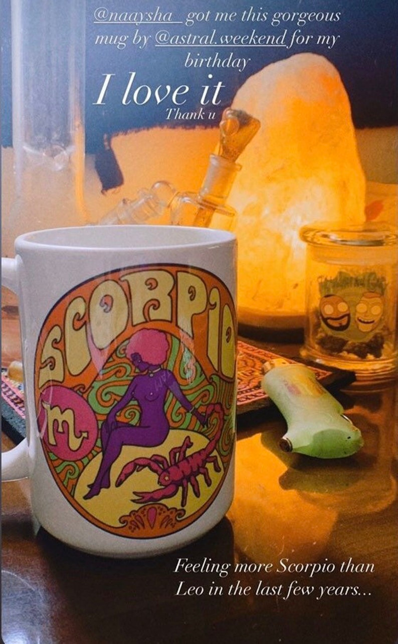 May include: White ceramic mug with a colorful illustration of a woman with a scorpion. The mug has the word "Scorpio" written in a retro font around the illustration. The text "I love it" and "Thank u" are written on the image.