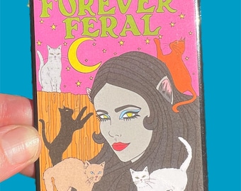 May include: A pink and black patch with the text "FOREVER FERAL" in green letters. The patch features a woman with long black hair and cat ears, surrounded by five cats. The cats are white, orange, black, and brown.
