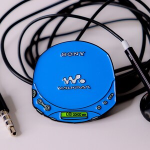 May include: A blue Sony Walkman CD player with a black cord and black headphones. The player has a digital display that reads "00 00 00".