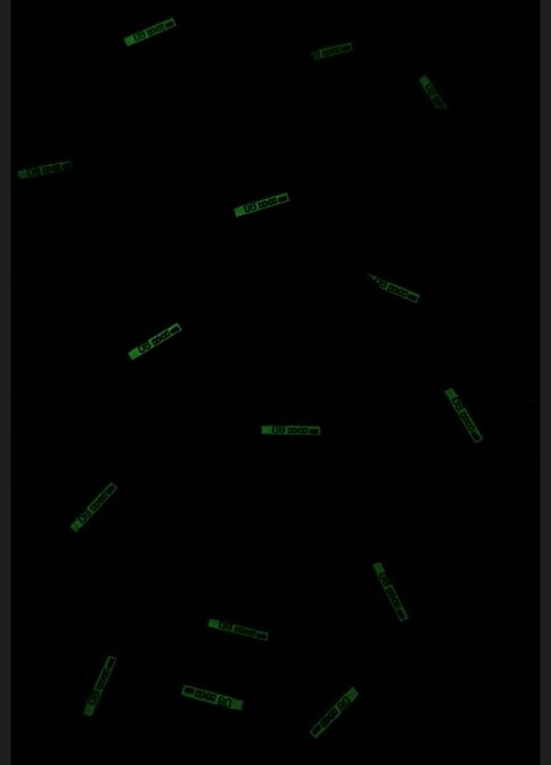 May include: A black background with multiple green glow-in-the-dark stickers that say "100 0000-00".