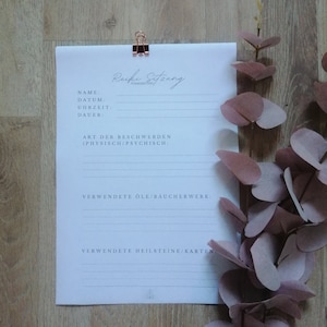 Puede incluir: Una hoja de papel blanca con el título "Reiki Sitzung" y una lista de campos para rellenar, incluyendo "Nombre", "Fecha", "Hora", "Duración", "Tipo de quejas (Físicas/Psíquicas)", "Aceites/Incienso utilizados", y "Piedras curativas/Cartas utilizadas".