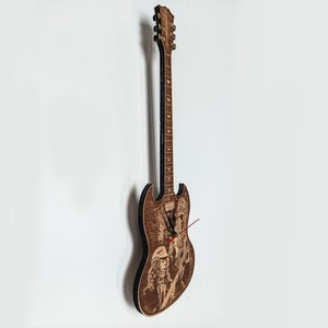 Könnte beinhalten: Eine Wanduhr in Form einer Gitarre aus Holz mit schwarzem Zifferblatt und roten Zeigern. Die Gitarre ist mit einem eingebrannten Bild einer Band verziert.