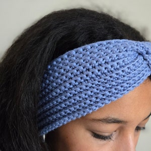 Pode incluir: Uma faixa de cabeça de tricô azul com um design de torção. A faixa de cabeça é feita de um material macio e confortável e é perfeita para manter o cabelo fora do rosto.